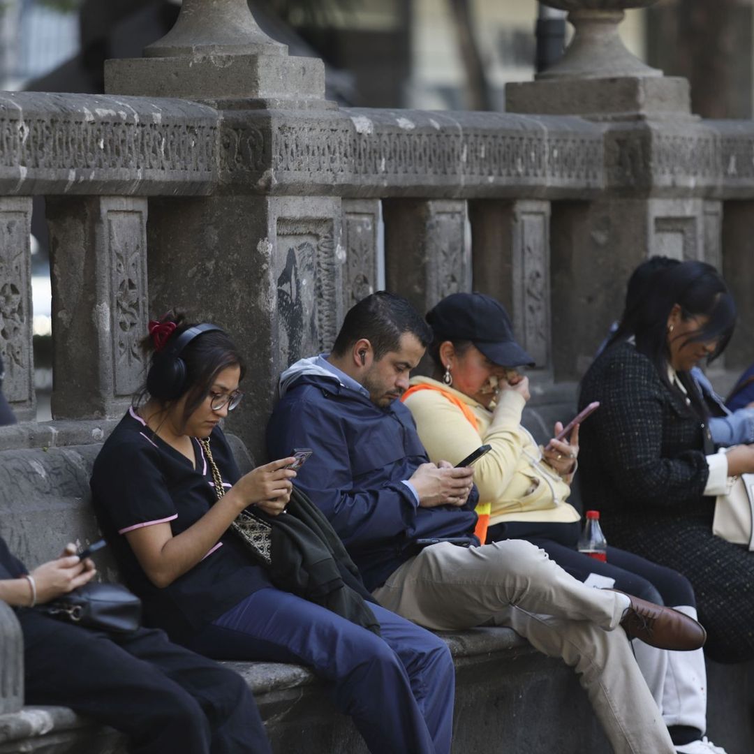 Capitalinos usan el celular mientras descansan en una de las bancas de Avenida Reforma. Foto: Cuartoscuro